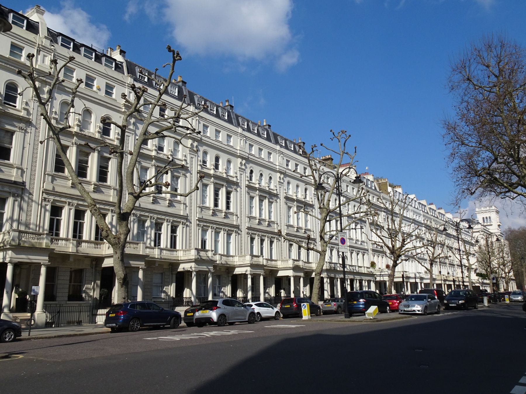 A row of white stucco London townhouses beneath a blue sky